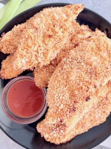 Plate with fresh air fryer chicken tenders with buffalo flavoring & sauce.