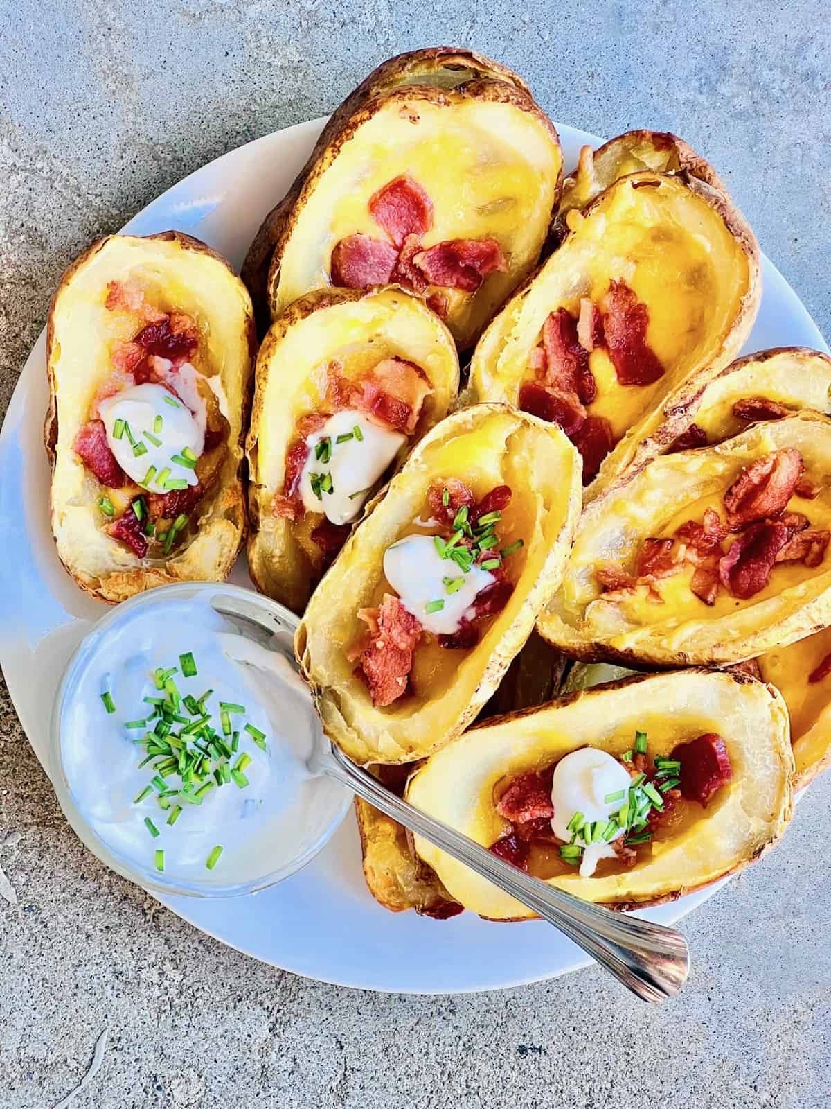 Air Fryer Loaded Potato Skins Plate with loaded stuffed potato skins with cheese and bacon dollops of sour cream.