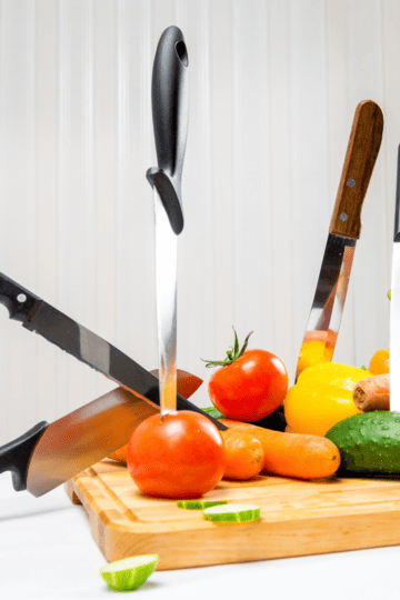 Best Knives for Cutting Vegetables Knives sticking out of veggies on a board,