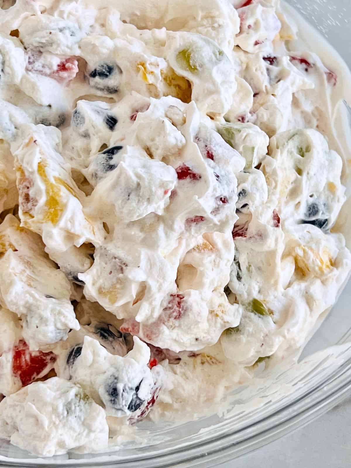Fruit Salad with Cool Whip Closeup in glass mixing bowl.