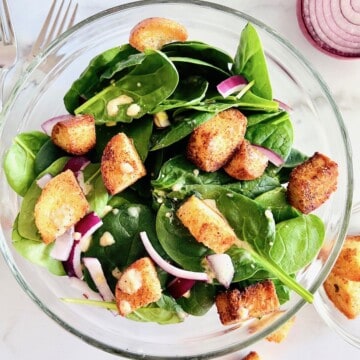 Glass serving bowl with a quick & easy spinach salad with simple ingredients.