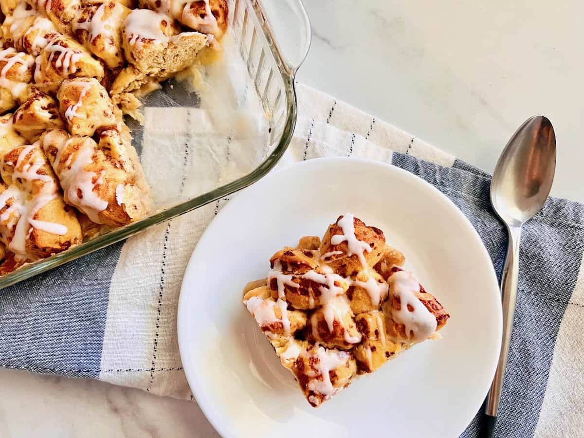 Plate with a square slice of peach cobbler with cinnamon roll topping. 