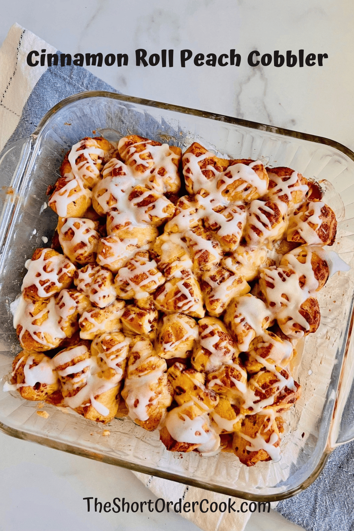 Cinnamon Roll Peach Cobbler in a baking dish topped with an icing drizzle. 