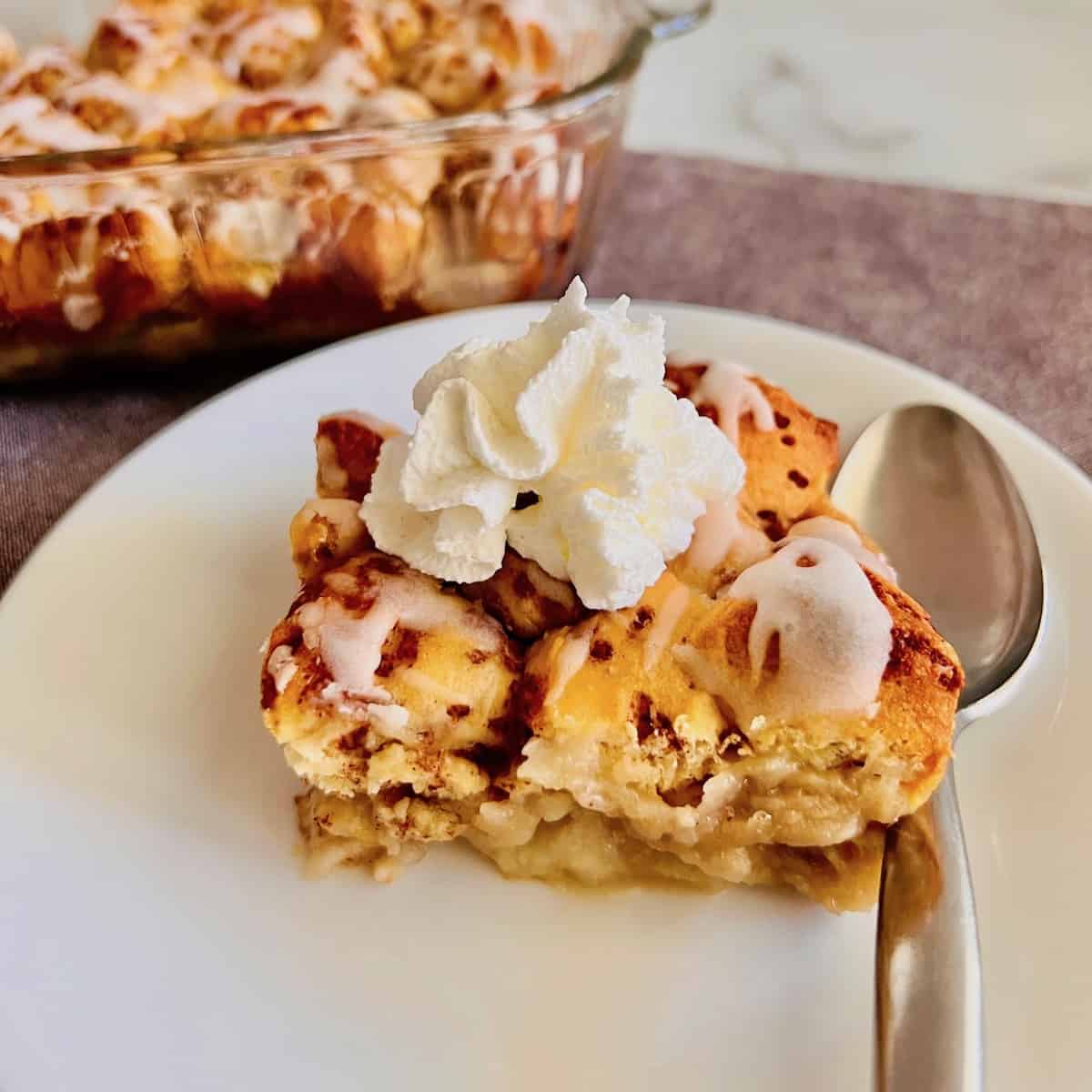 Cinnamon Roll Peach Cobbler topped with a dollop of canned whipped cream.