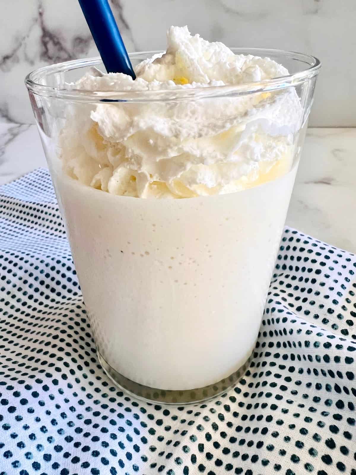 Coconut Milkshake Closeup with whipped cream straw and polka dot napkin.