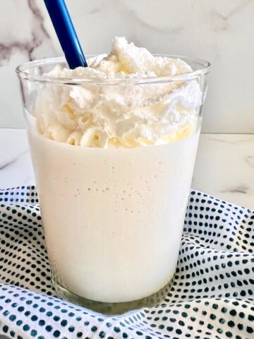 Glass of coconut milkshake with whipped cream.