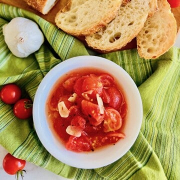 Marinated Italian tomatoes with olive oil and garlic in a bowl for dipping or topping on bread.