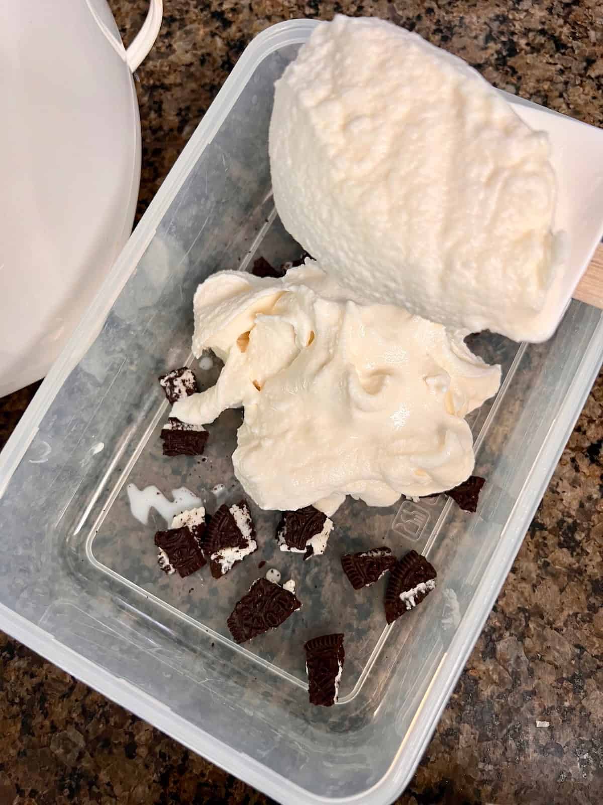 Oreo Cookies & Cream Ice Cream Adding vanilla ice cream over Oreo pieces in the container.