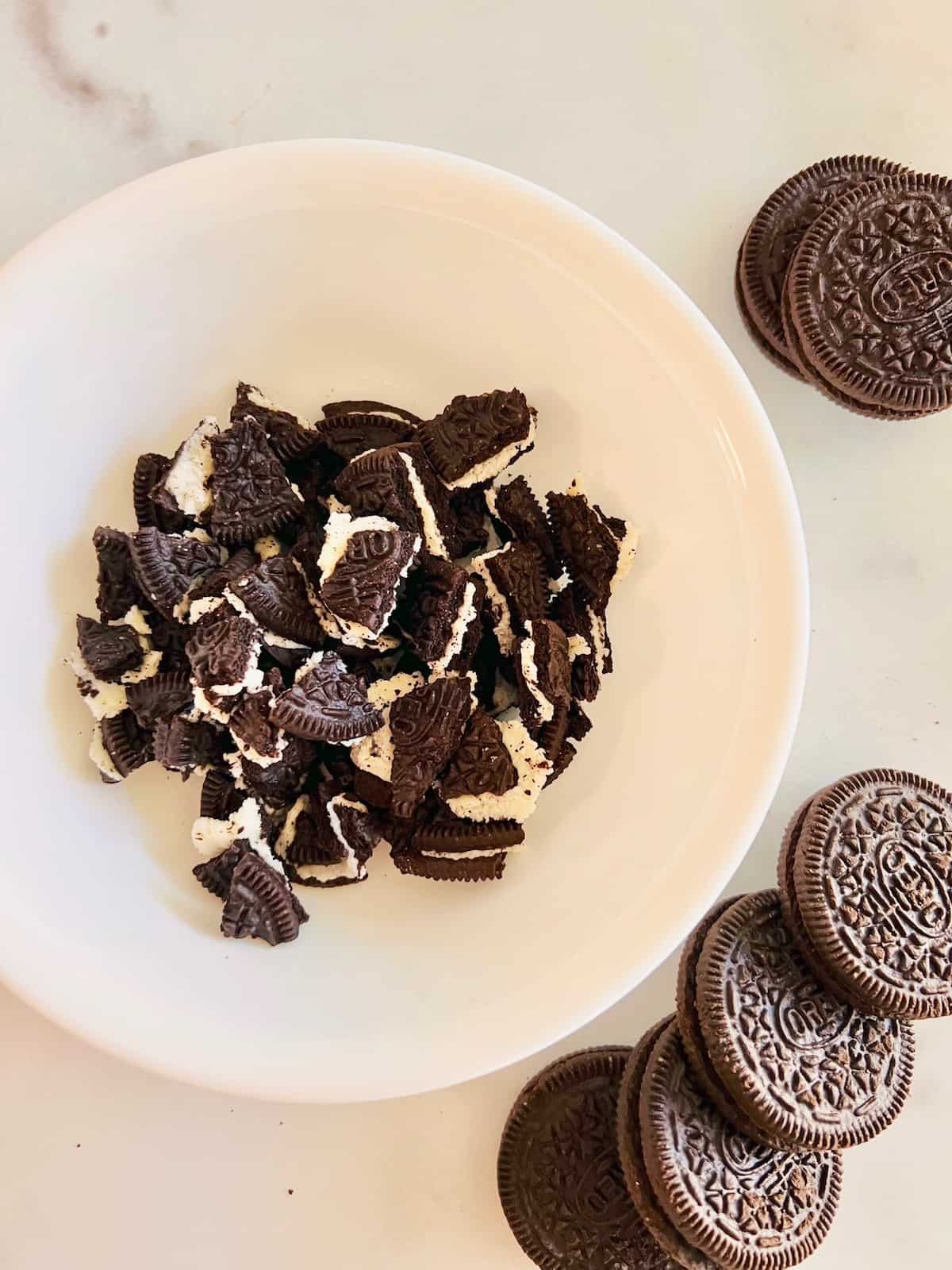 Breaking Oreos into bits and pieces in a bowl.