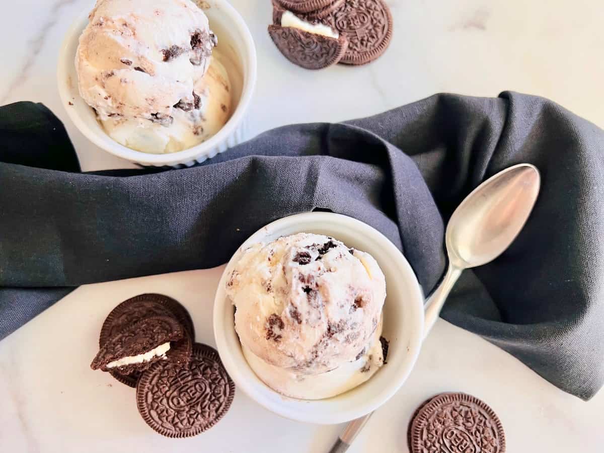 Vanilla ice cream loaded with broken Oreo cookie sandwiches scooped into two bowls..