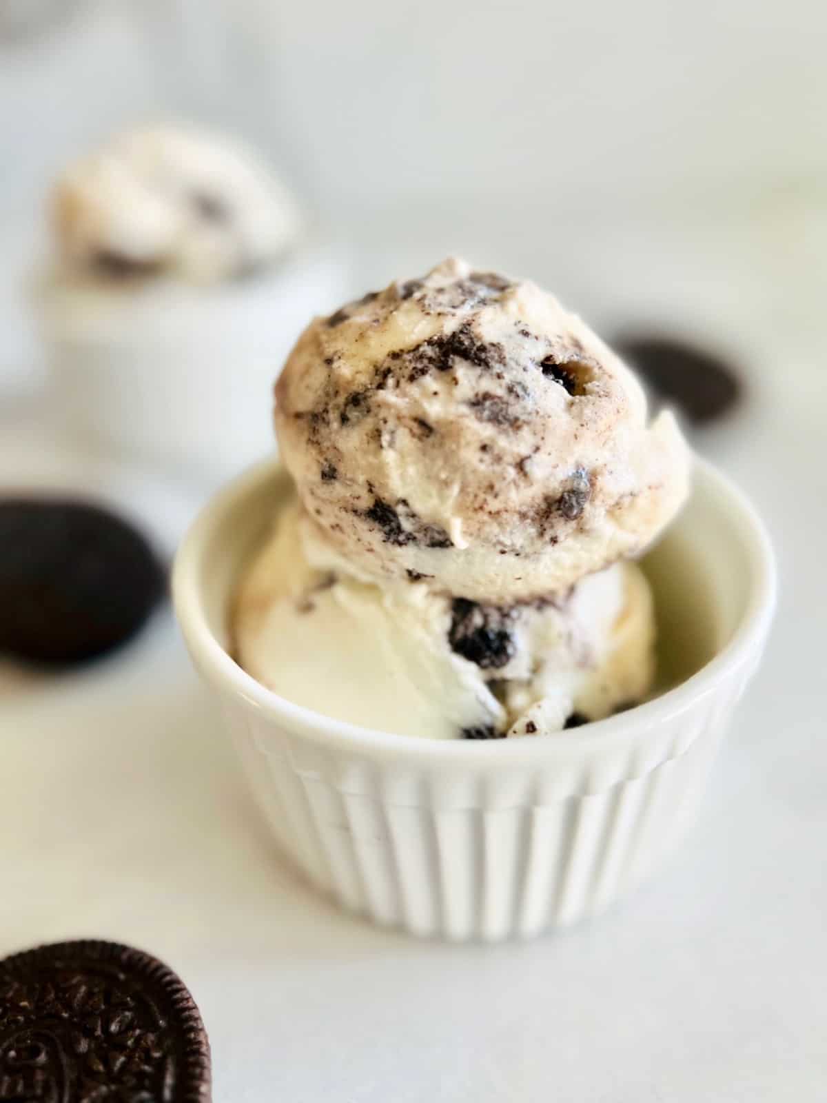 Oreo Cookies & Cream Ice Cream Portrait side view of ramekin with two scoops and Oreos on the side.