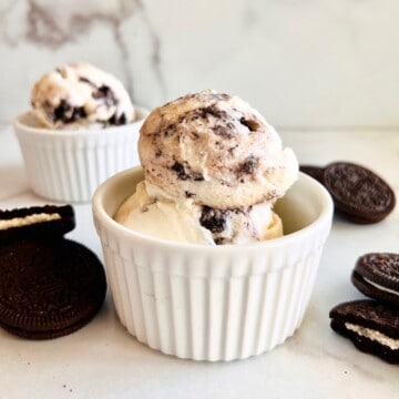 Oreo Cookies & Cream Ice Cream Recipe Card side view of scoops in white bowls next to Oreos.