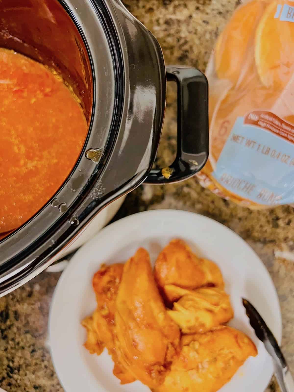 Chicken breasts removed from the slow cook to shred in a plate.