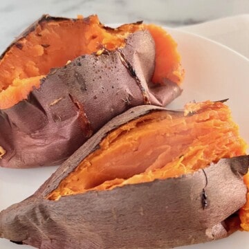 Two sweet potatoes cut open exposing the orange flesh inside.
