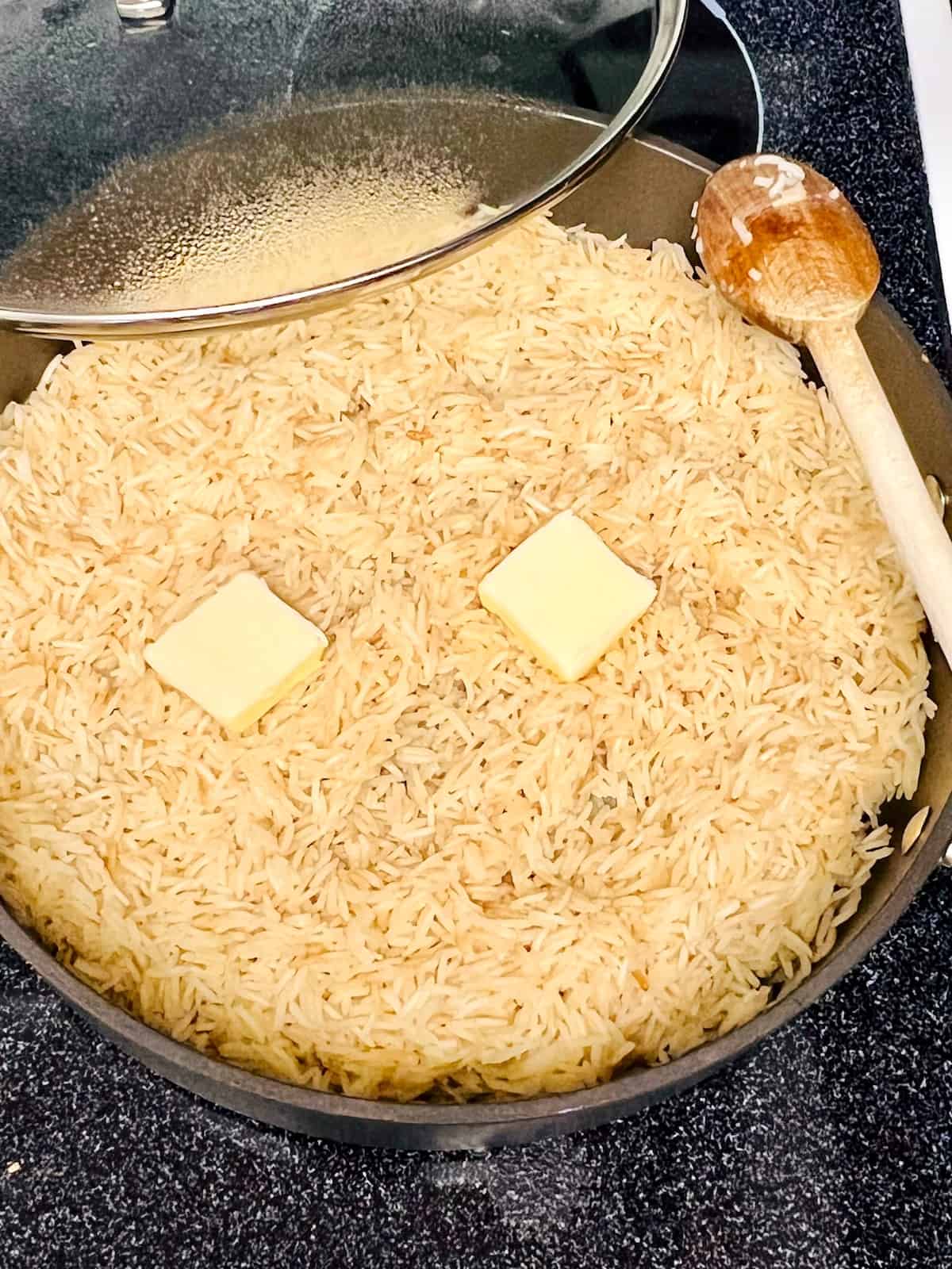 Chicken Broth Rice Adding the butter to the cooked rice in the pan.