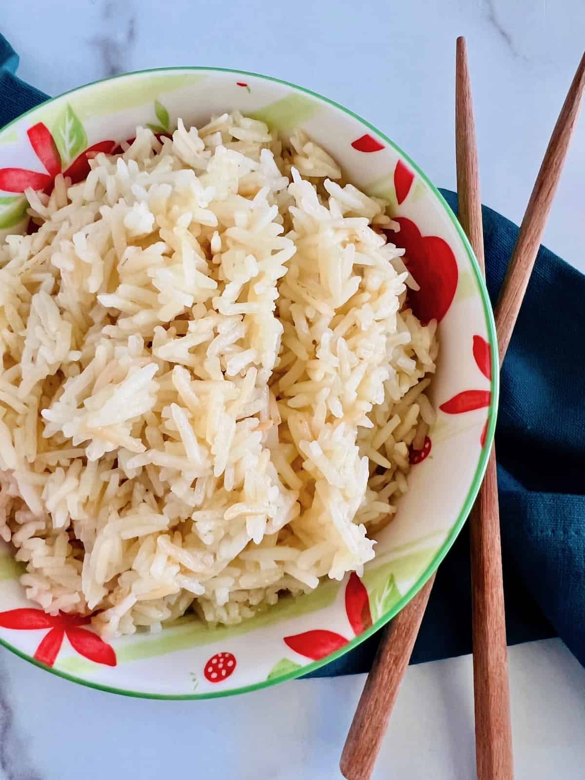 Chicken Broth Rice In a bowl with chopsticks to the side and blue linen napkin.