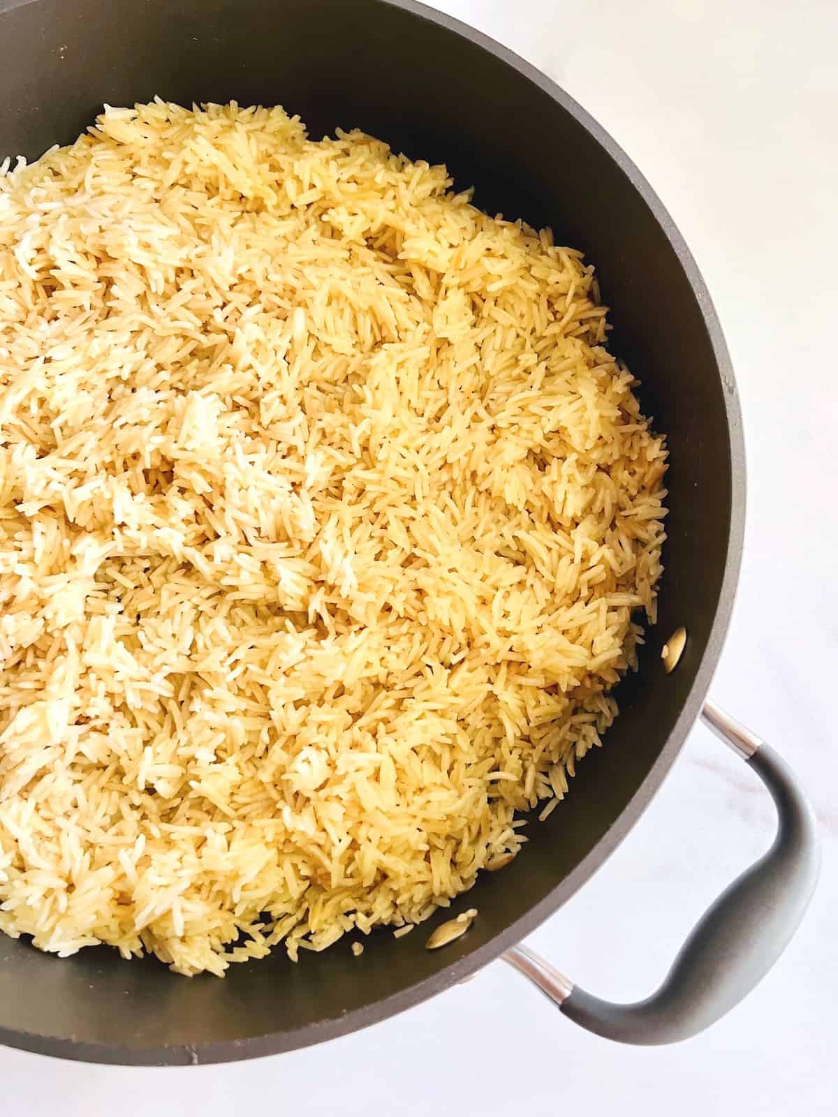 Overhead of pot filled with cooked chicken broth and butter rice.