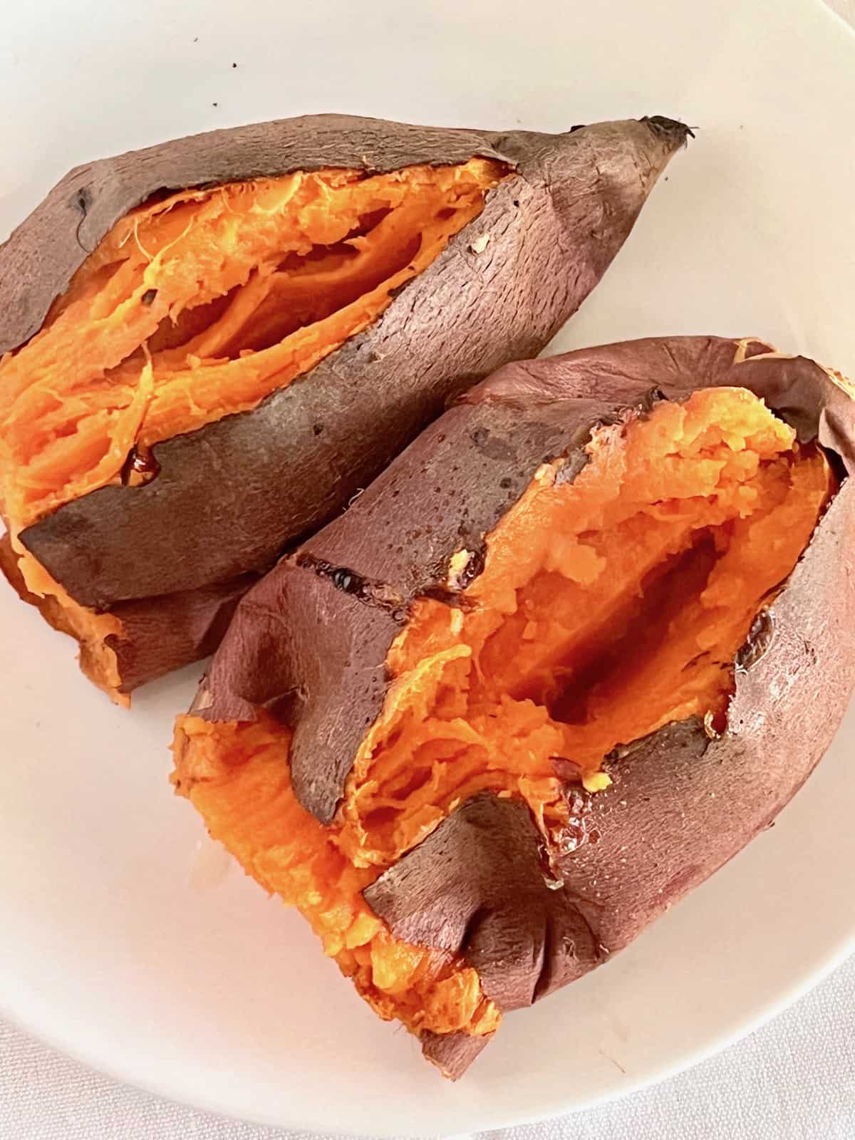 Baked sweet potatoes on a plate split open.