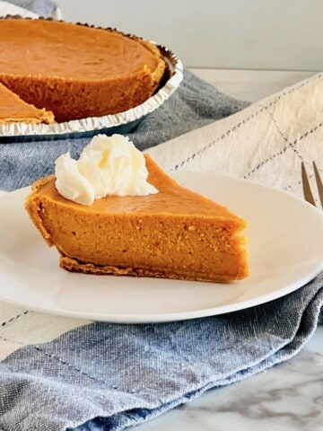 Graham Cracker Crust Sweet Potato Pie Featured Slice plated with whole pie in background sideview.