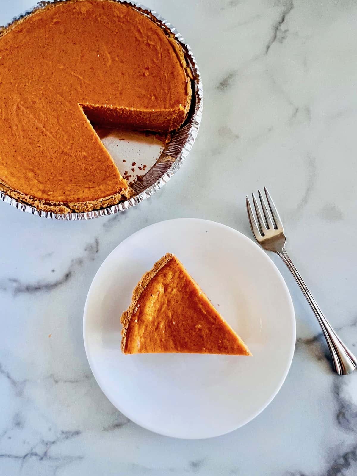 Graham Cracker Crust Sweet Potato Pie Whole pie with a slice cut out and plated next to a fork.