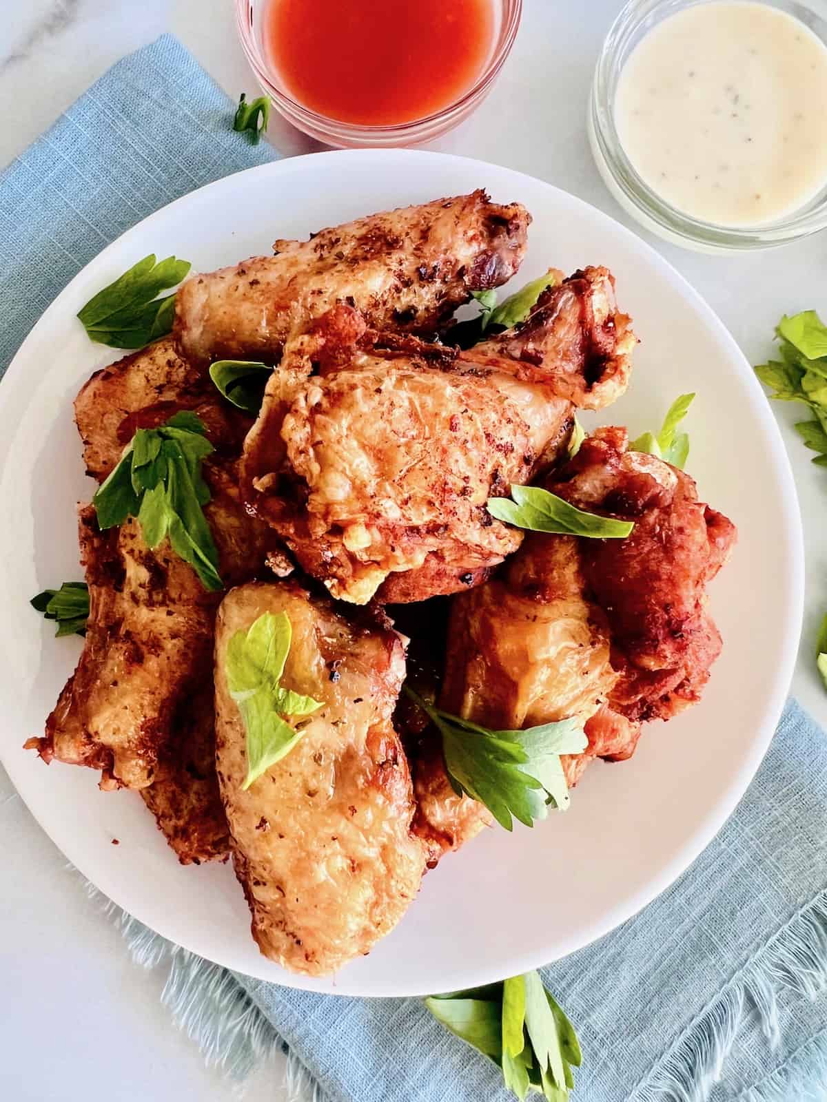 Naked Chicken Wings Plated with parsley sprinkled on top next to dips.