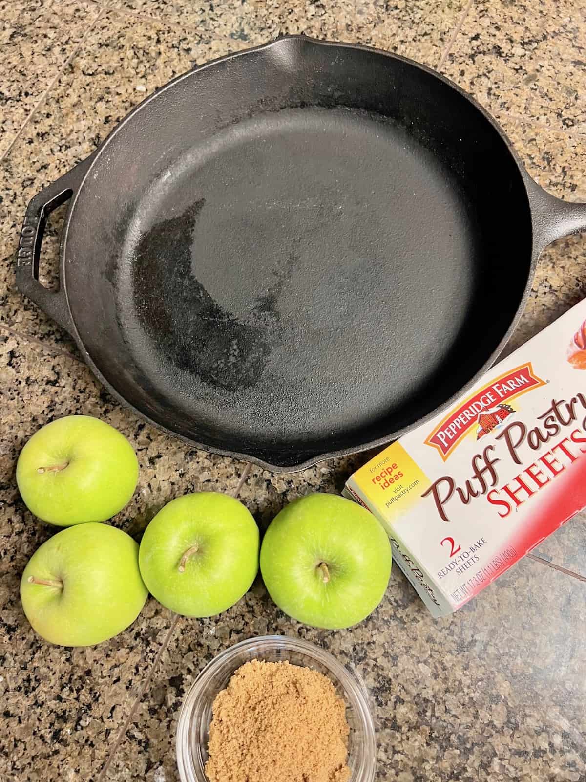 Cast iron skillet box of puff pastry and apples on the counter.