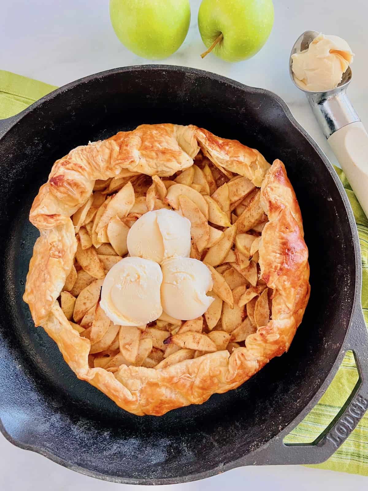 Puff Pastry Apple Galette Topped with scoops of vanilla ice cream with a scoop to the side.