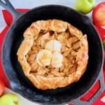 Puff Pastry Apple Galette in a cast iron skillet topped with 3 scoops of ice cream and caramel sauce.