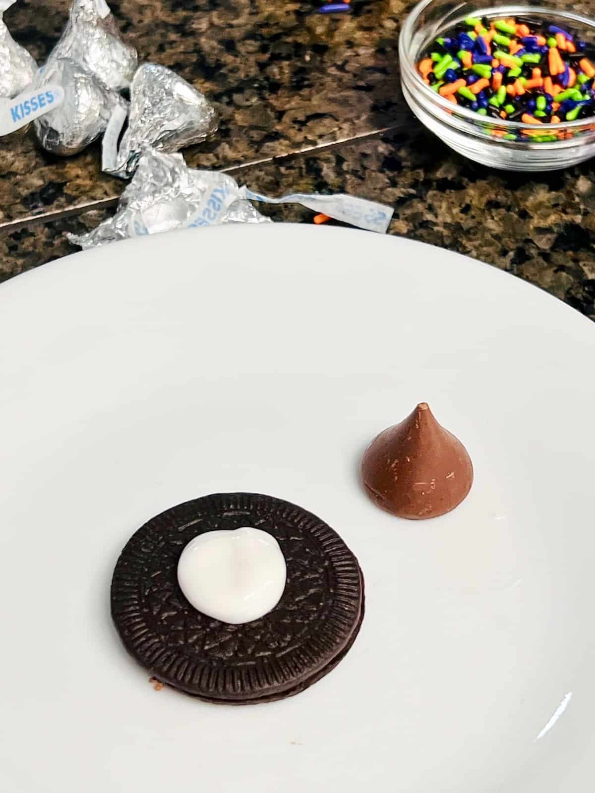 Witch Hat Cookies A plate with an Oreo Thin topped with a dollop of white icing.