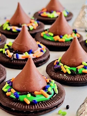 Oreo cookies topped with frosting and chocolate kiss candy to look like pointed witch hats.