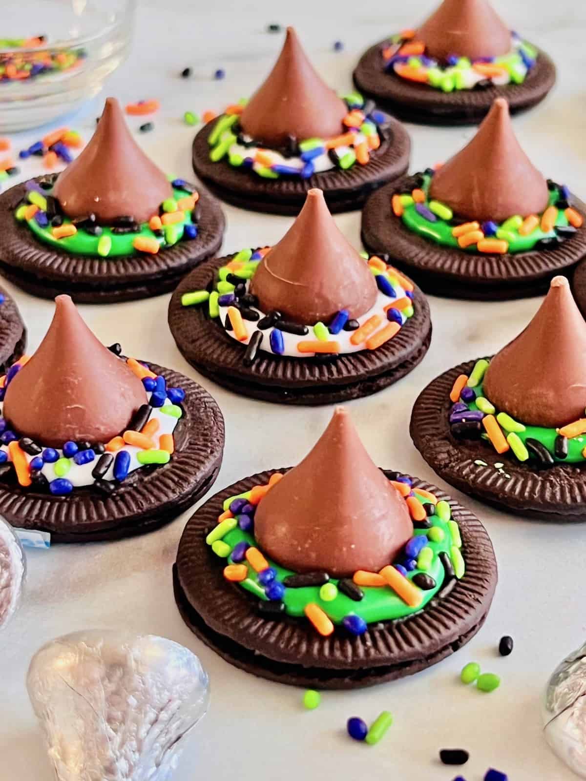 Witch Hat Cookies Lined up on the counter with wrapped Hersheys kisses and sprinkles.