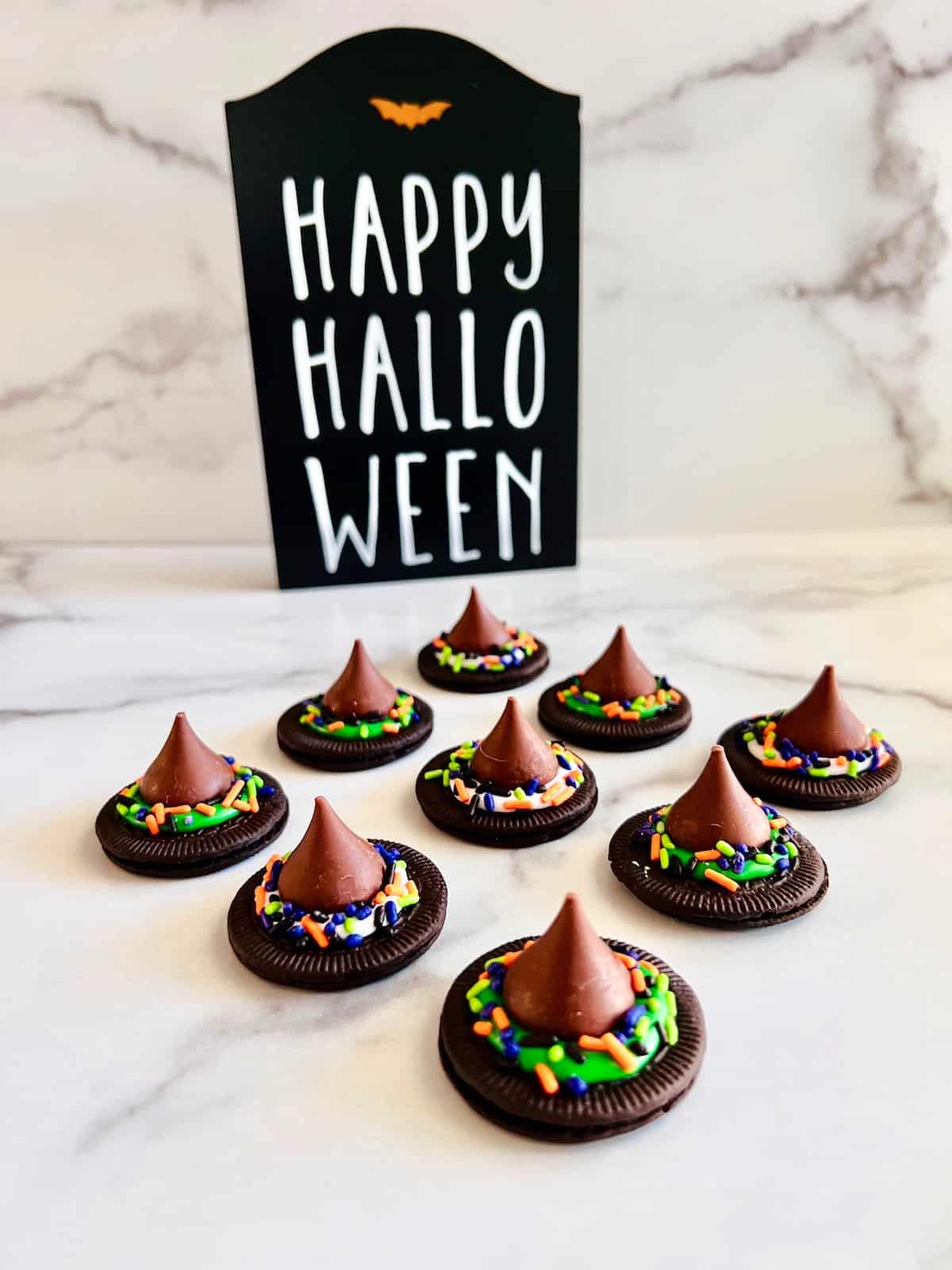 Witch Hat Cookies On a counter with happy halloween sign.