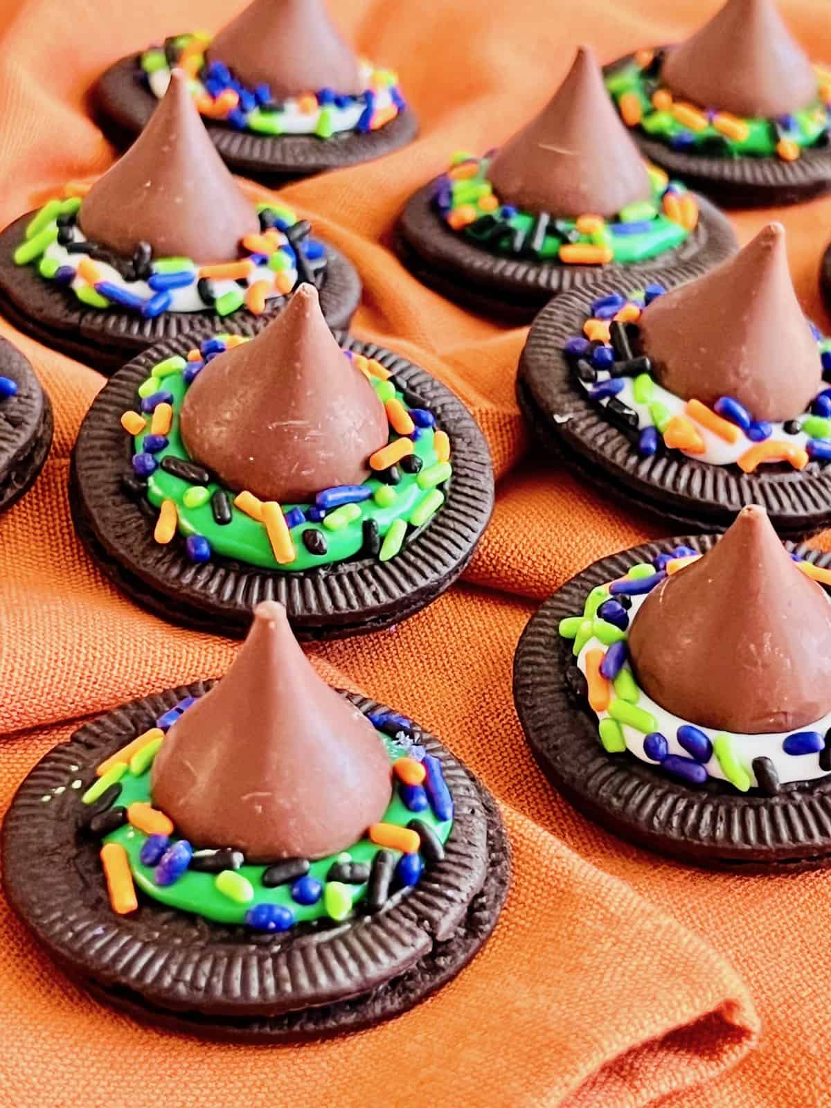 Oreo Cookies decorated to look like Halloween Witch Hats On an orange cloth napkin.