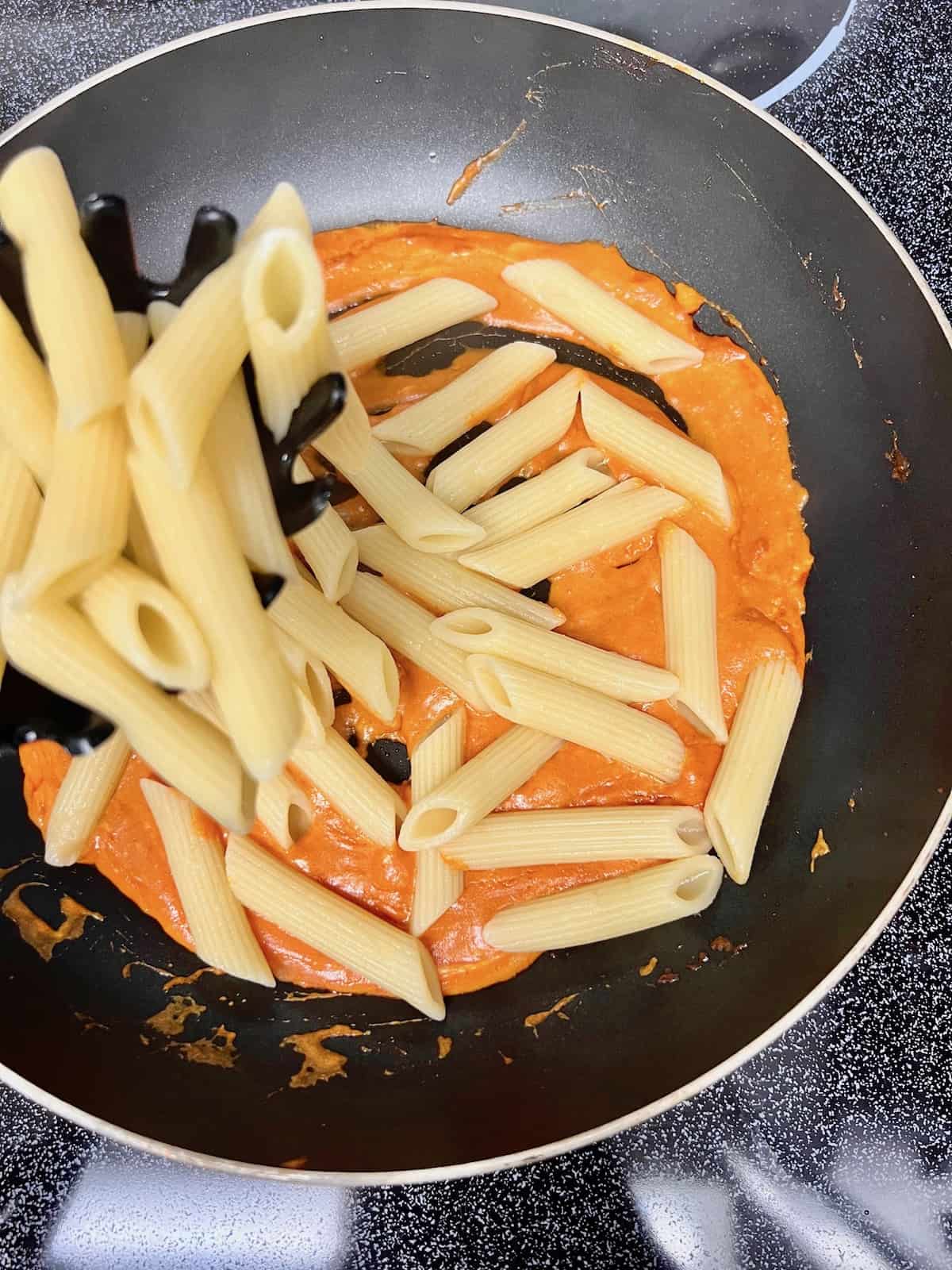 Adding pasta to the pan.