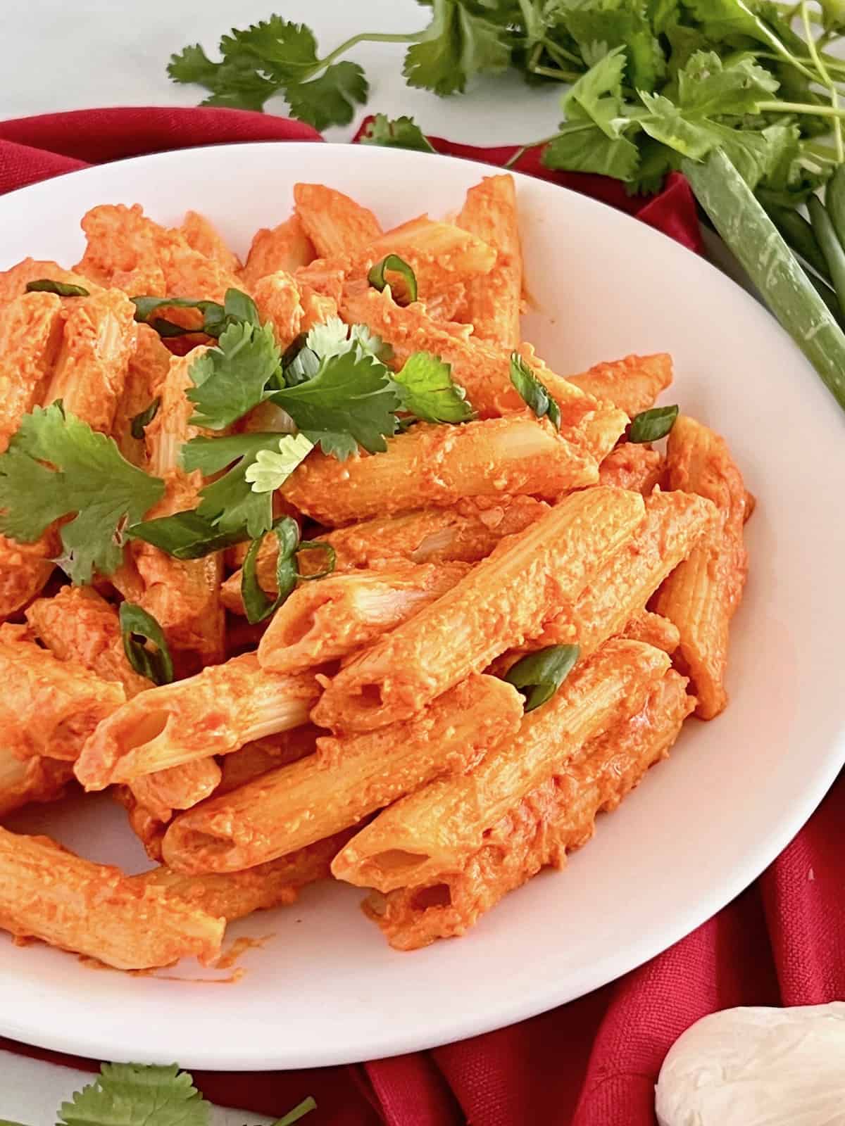 Gochujang Pasta plated with added toppings of parmesan, cilantro leaves, and scallion slices. 