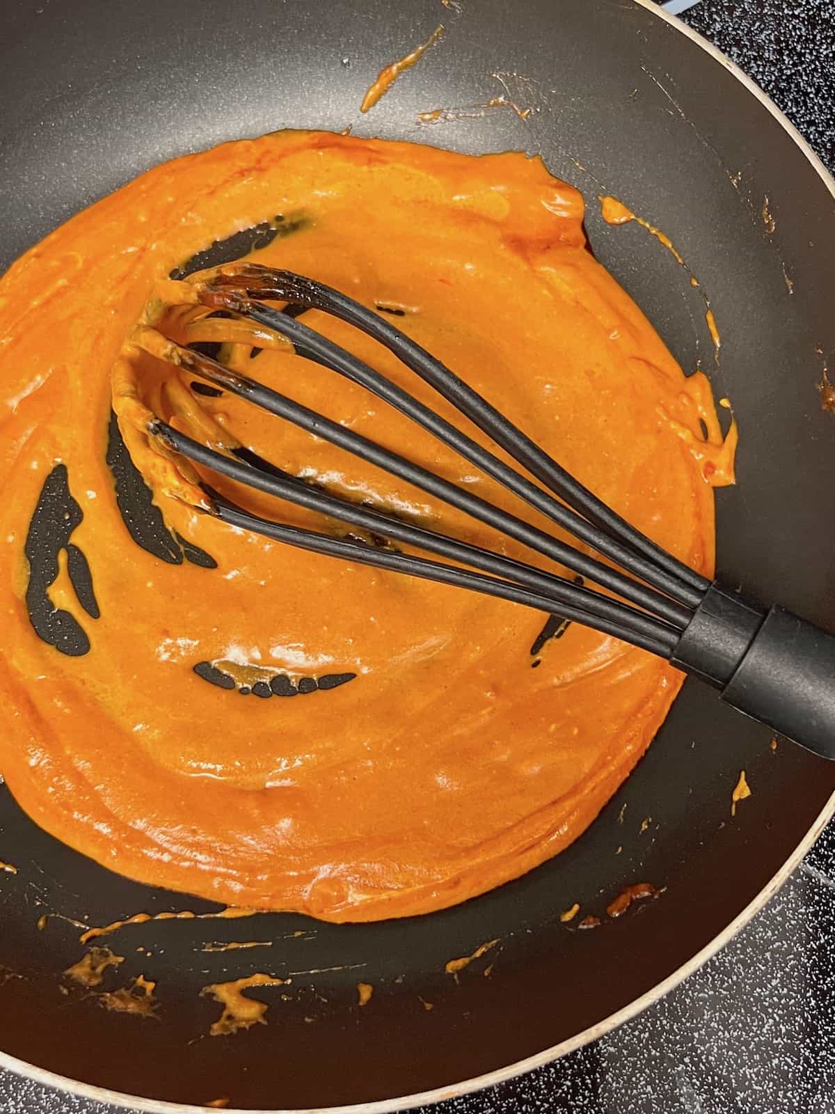 Whisking the melted cream cheese into the gochujang sauce.