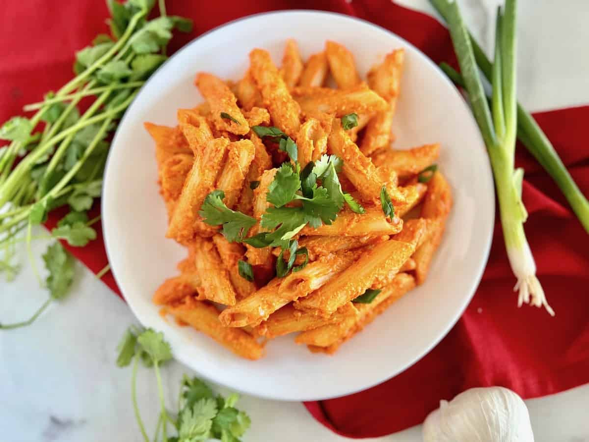 Creamy Gochujang Pasta with parmesan cheese in a bowl topped with fresh cilantro and green onion.