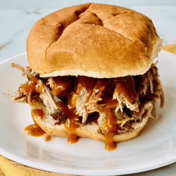 Burger Bun piled with pulled pork and barbecue sauce.