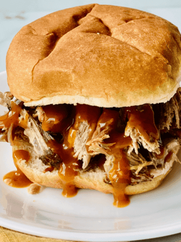Burger Bun piled with pulled pork and barbecue sauce.