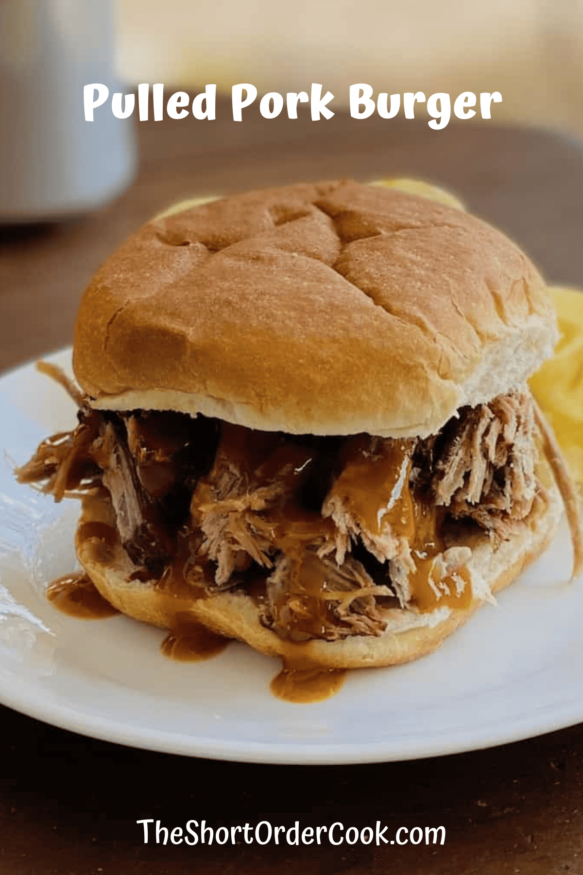 A round bun filled with shreds of pulled pork drizzled with bbq sauce. 