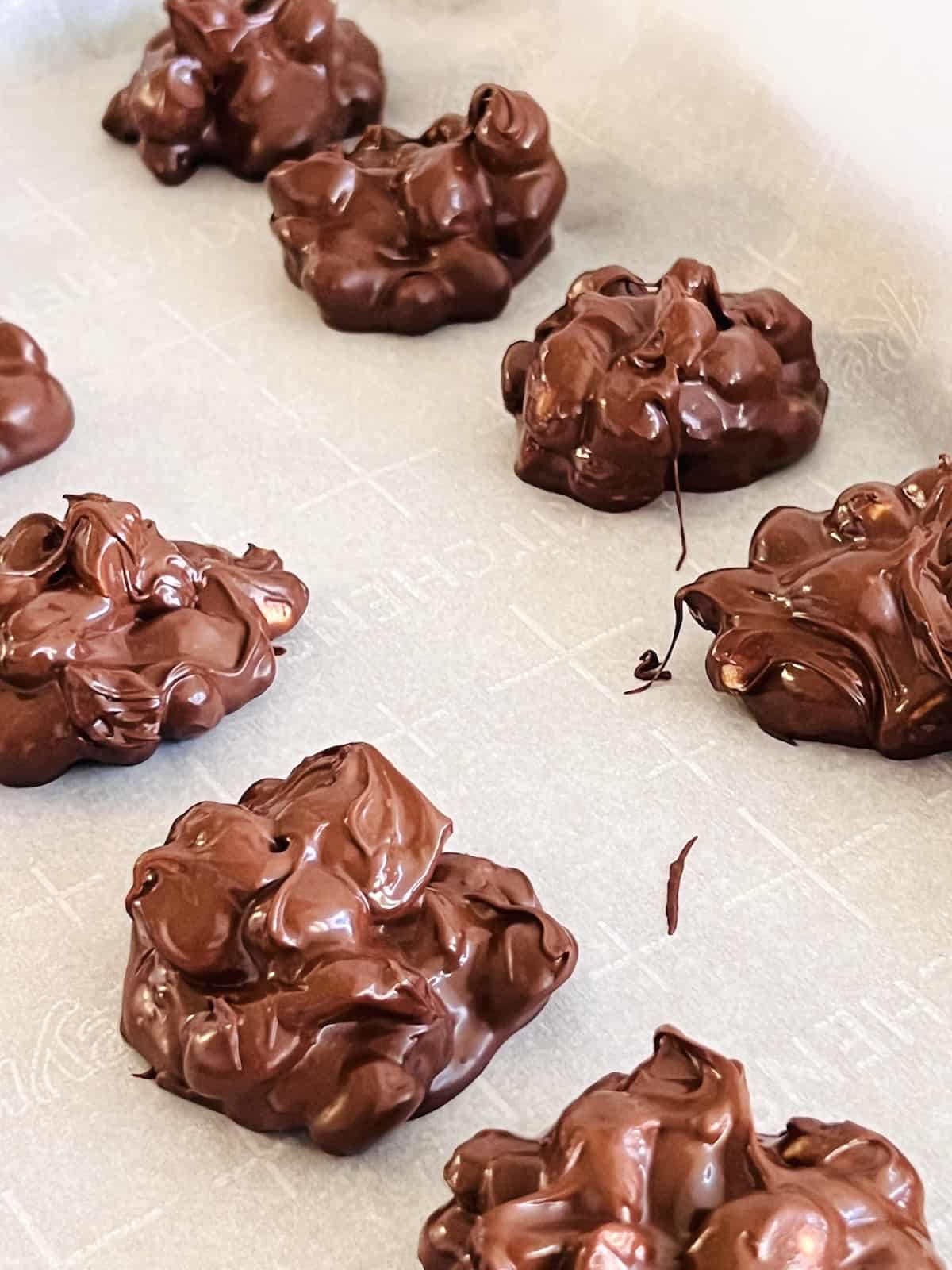 Chocolate Peanut Clusters Drops on parchment to set.