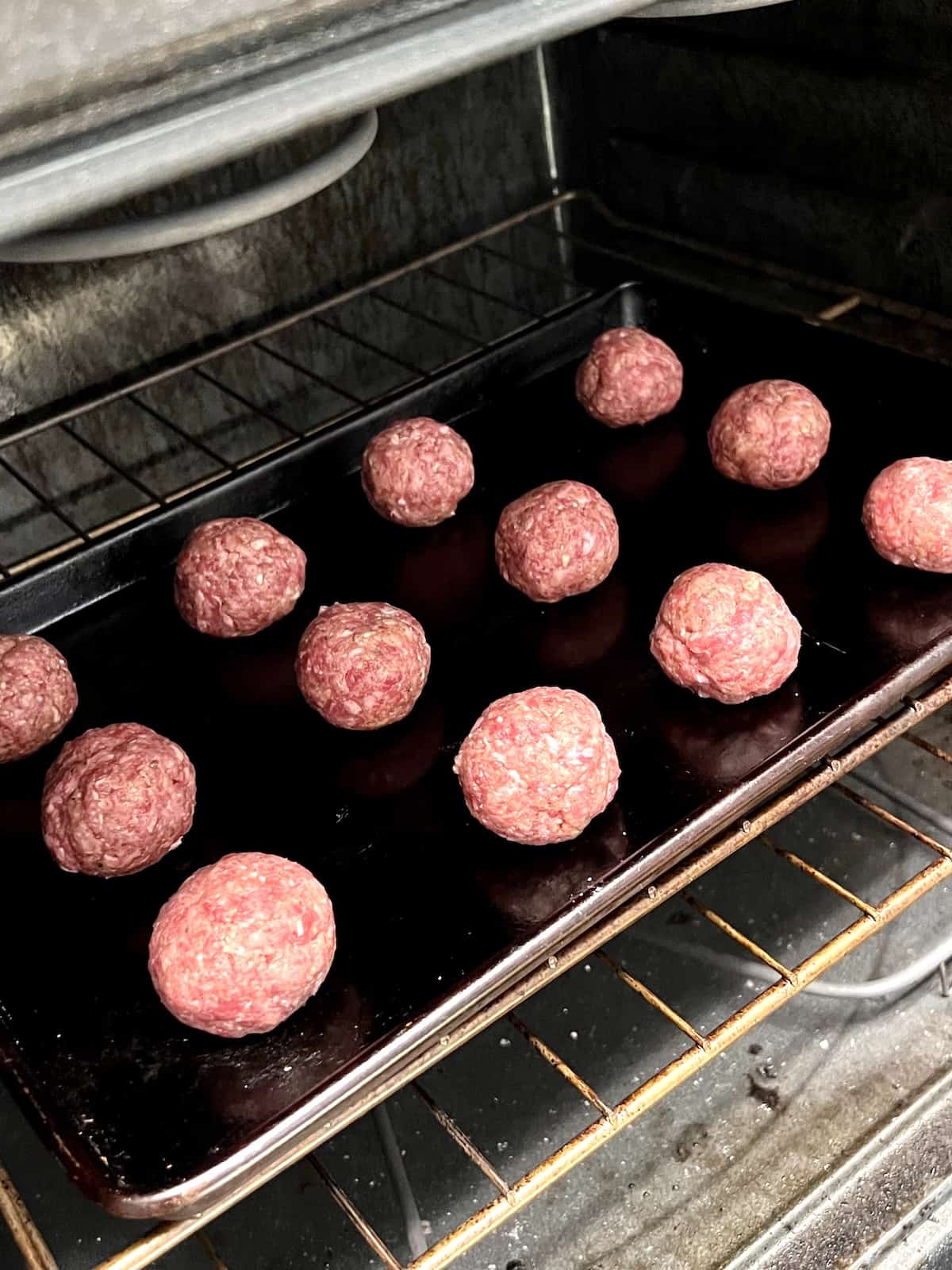 Raw Meatballs on sheet pan going into the oven.