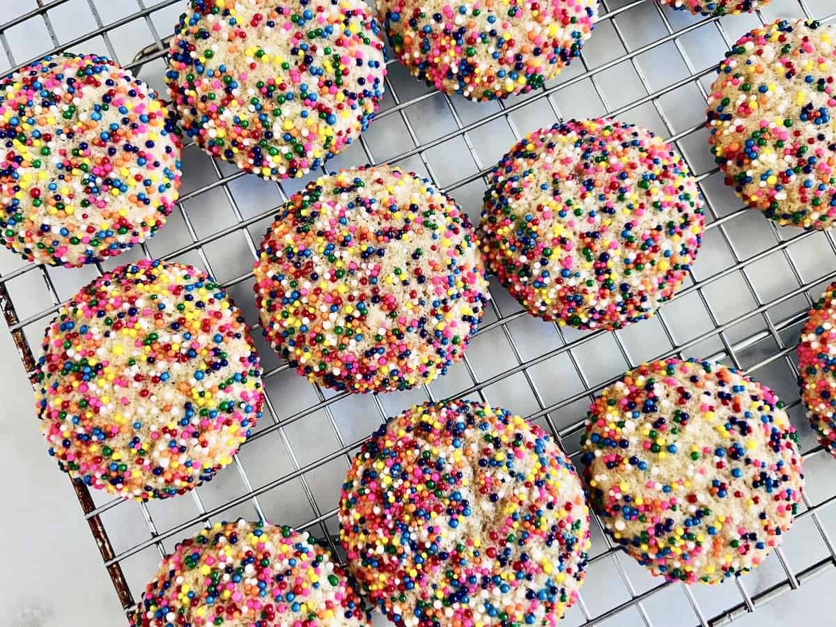 Sugar Cookies with rainbow nonpareil sprinkles cooling on a wire rack.