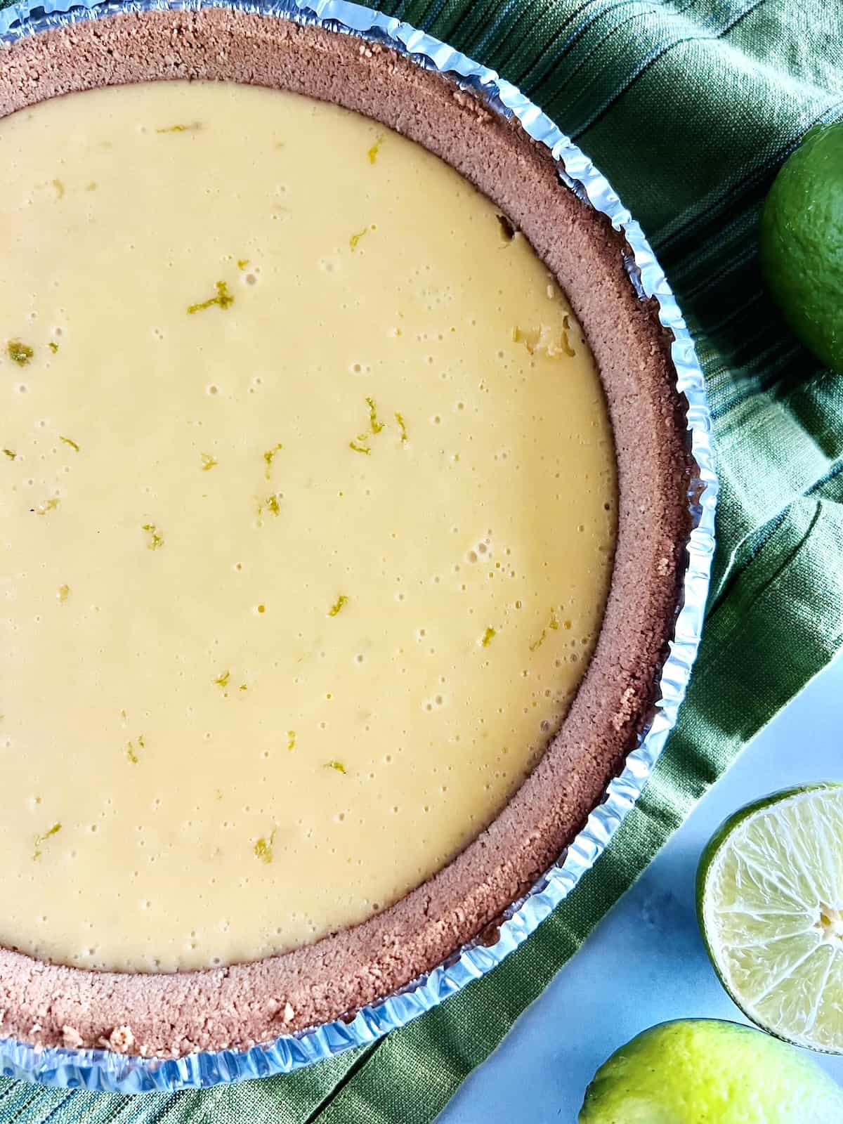 Key lime pie done baking with golden yellow color with specks of green zest on top. 