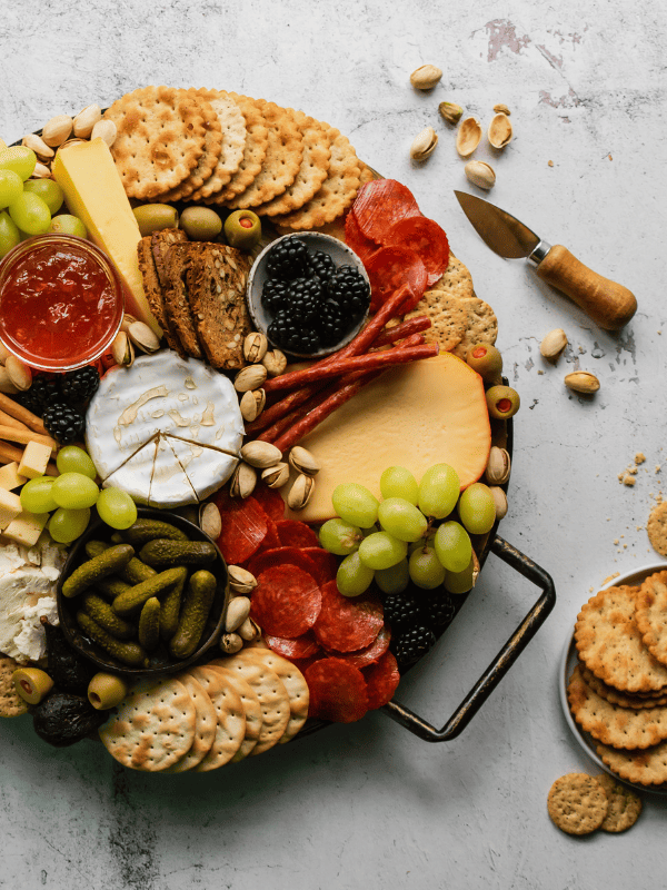 Charcuterie board with crackers, cheese, meats and fruits displayed.