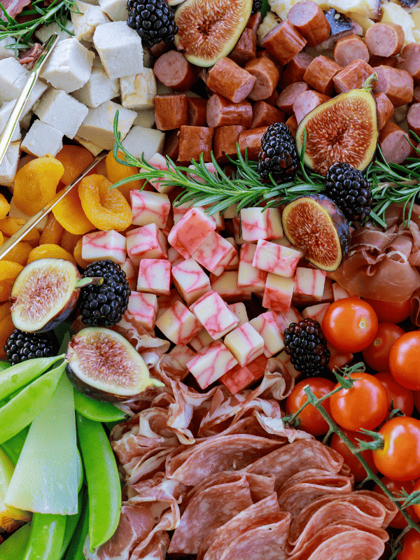 Variety of cubed meats, cheeses, sliced fruit, and vegetables.