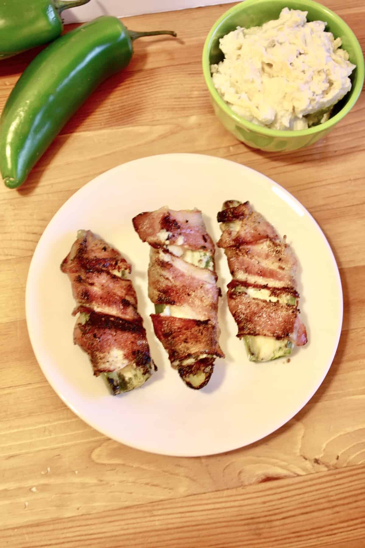 Grilled Jalapeño Poppers Plated next to bowl of dip and whole peppers.