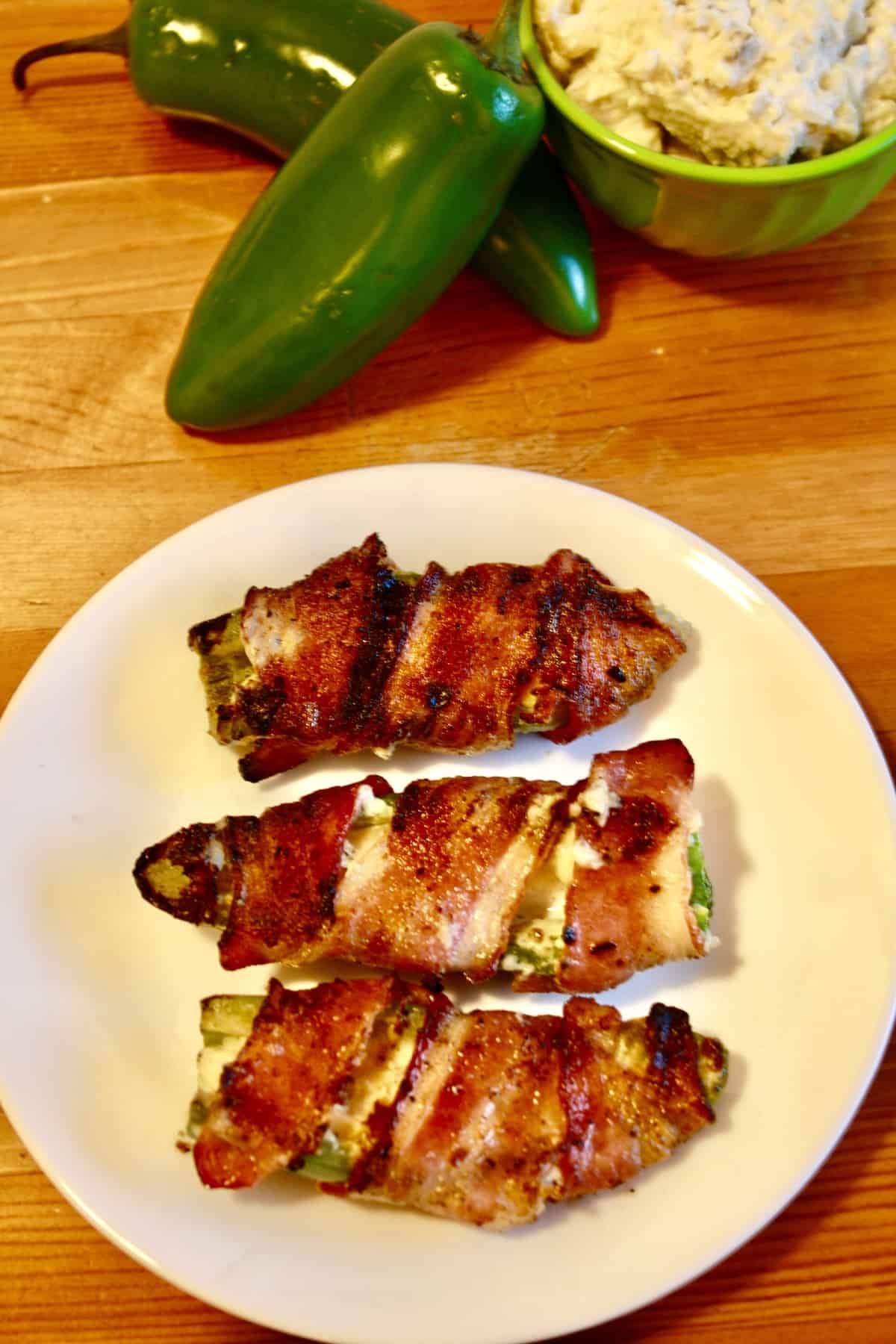 Grilled Jalapeño Poppers Plated ready to eat next to whole peppers and bowl of artichoke dip.