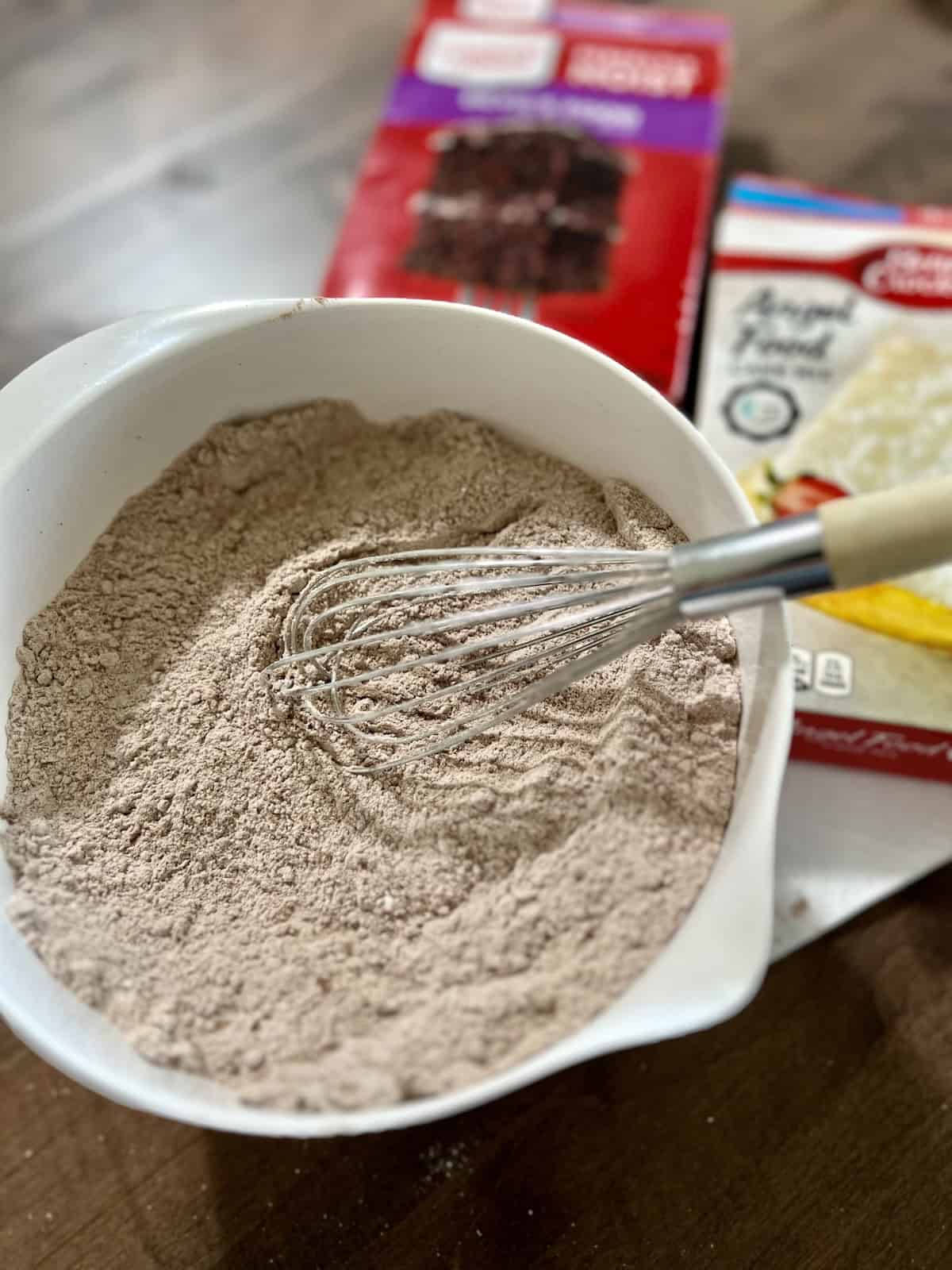 Mixing 2 boxed cake mixes in a bowl for storing to use later for microwave mug cakes.