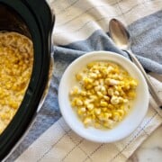 Bowl and Crockpot full of slow cooker creamed corn